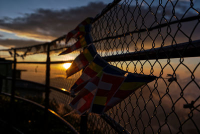Chainlink fence against sky during sunset
