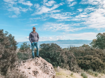 Full length of man standing on rock against sky