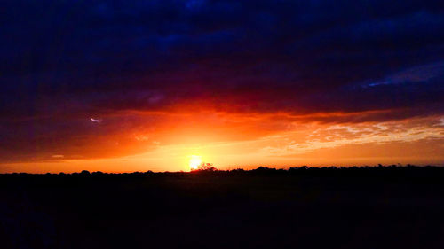 Silhouette landscape against dramatic sky during sunset