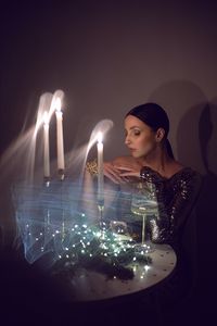 Portrait of woman standing by illuminated string lights