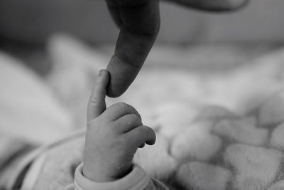 Cropped image of father touching baby finger