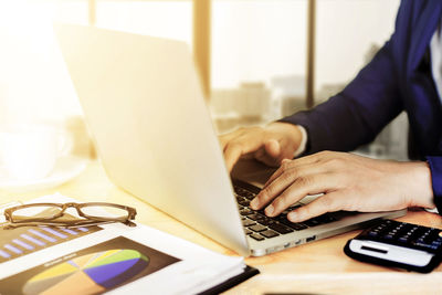 Midsection of man using laptop on table