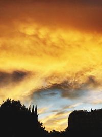 Low angle view of silhouette trees against dramatic sky