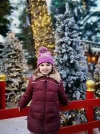 Portrait of smiling girl standing by tree during winter