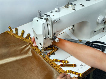 Cropped hand of woman working on sewing machine