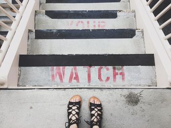 Low section of woman standing on staircase with text