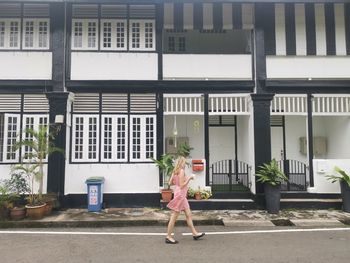 Woman walking on footpath against building