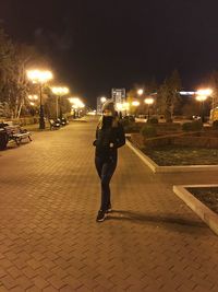 Full length of woman on illuminated street at night