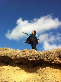 Low angle view of woman jumping against sky