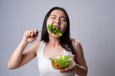 Young woman eating food against white background