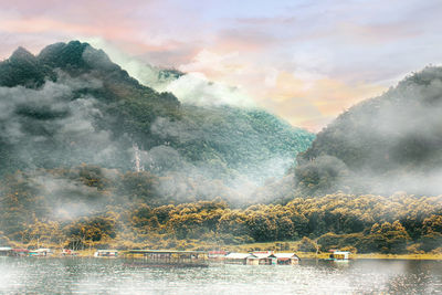 Panorama scenic of foggy mountain in autumn with rafting house on lake.