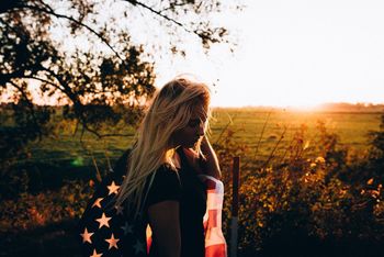 WOMAN STANDING ON GRASSY FIELD