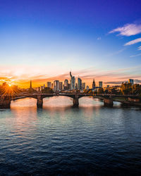 View of river and buildings against sky during sunset