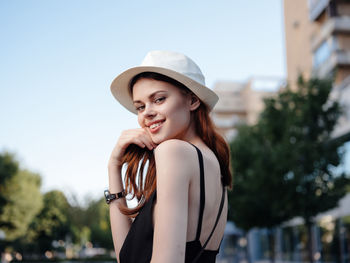 Side view of young woman wearing hat against sky