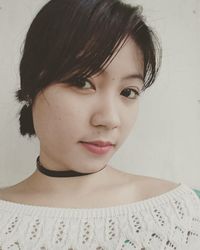 Close-up portrait of a young woman against wall