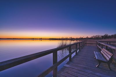 Pier over lake against sky during sunset