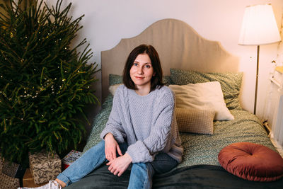 Portrait of young woman sitting on sofa at home