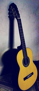 Close-up of guitar on table against wall