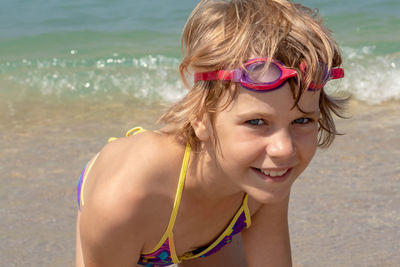 Portrait of young woman wearing sunglasses while standing at beach