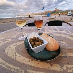 Close-up of beer on table at beach against sky