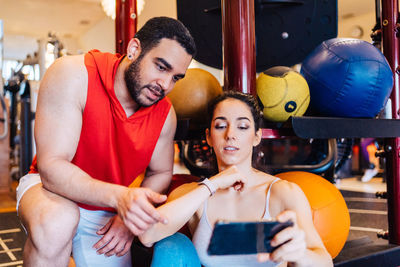 Portrait of couple in love at gym watching exercise on mobile phone