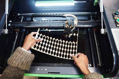 Cropped hands of woman using machinery