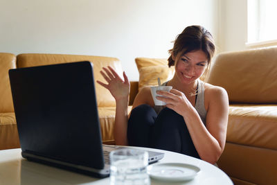 Young woman using mobile phone while sitting on sofa