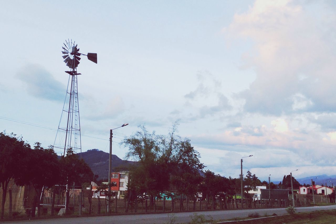 sky, tree, building exterior, built structure, architecture, cloud - sky, street light, house, cloudy, cloud, incidental people, day, nature, outdoors, town, road, palm tree, street, scenics, flag