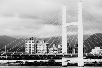 Suspension bridge in city against sky