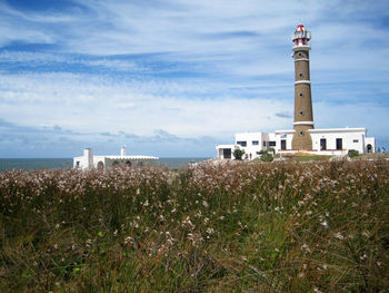 Lighthouse by sea against sky