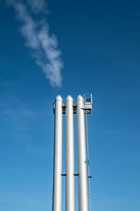 Low angle view of chimneys against blue sky