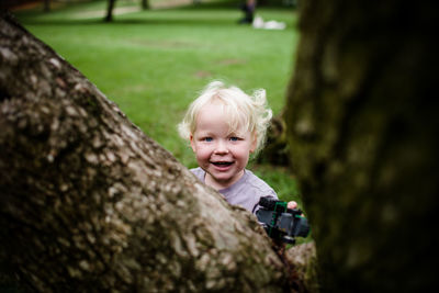 Portrait of smiling boy on tree trunk