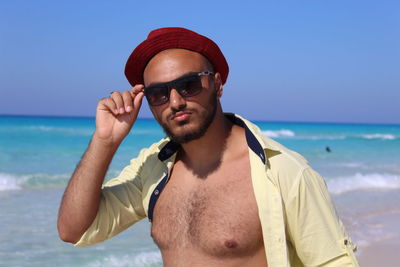 Portrait of woman wearing sunglasses while standing at beach