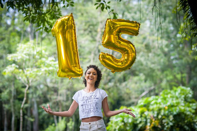 Portrait of smiling teenage girl holding 15 number balloons