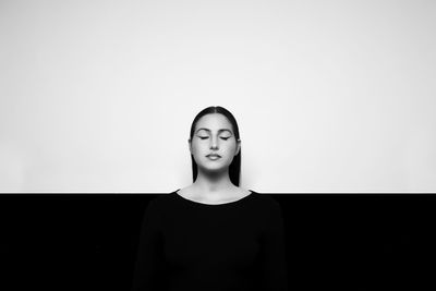 Portrait of woman standing against black background