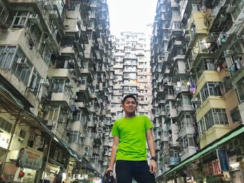 Low angle view of man standing amidst buildings in city