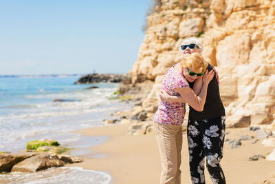 Two senior women are metting on a walk along a rocky beach