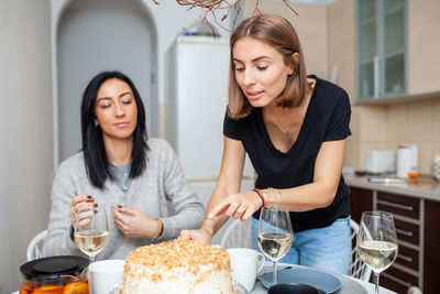 Beautiful women with food on table enjoying at kitchen