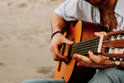 Midsection of man playing guitar