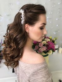 Side view of young woman with wavy brown hair during wedding