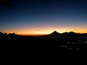 Silhouette cityscape against clear sky during sunset