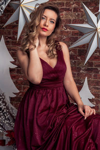 Portrait of young woman standing against wall