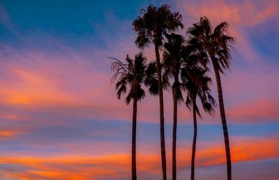 Silhouette palm trees against romantic sky at sunset