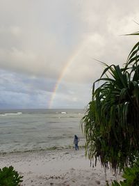 Scenic view of sea against rainbow in sky