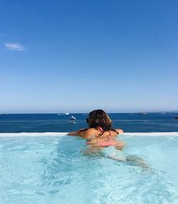 Young woman in swimming pool in sea against sky