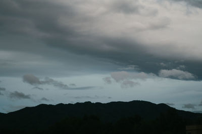 Low angle view of silhouette mountain against storm clouds