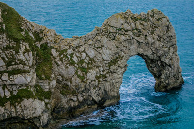 Rock formations by sea against blue sky