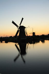 Traditional windmill with reflection against sky during sunset