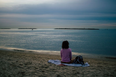 Rear view of woman sitting on beach