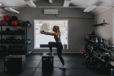 Side view of young woman training in gym